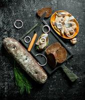 pièces de salé hareng avec noir pain et herbes. photo