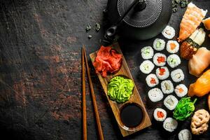 différent les types de Japonais Sushi, Rouleaux et maki avec sauce, wasabi et vert thé dans une théière. photo