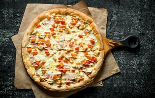 Pizza avec poulet, tomates et fromage sauce sur papier. photo