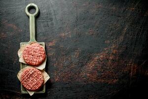 brut des hamburgers sur une Coupe planche avec papier. photo