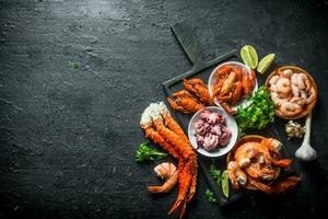 divers Fruit de mer sur une Coupe planche avec ail, citron vert et persil. photo