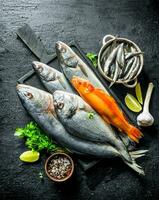 divers Frais poisson sur une Coupe planche avec épices, persil, Ail et chaux. photo