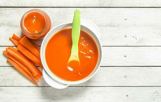 bébé aliments. bébé purée de Frais carottes avec une cuillère. photo