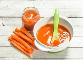 bébé aliments. bébé purée de Frais carottes avec une cuillère. photo