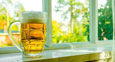 verre de Frais Bière sur le rebord de fenêtre dans été. photo