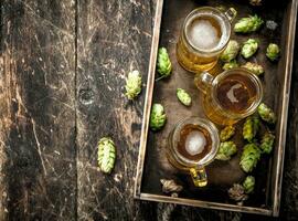 Frais Bière dans des lunettes avec vert le houblon sur un vieux plateau. photo