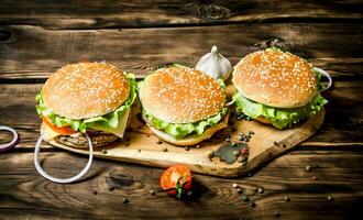 Trois fini Burger avec Viande et des légumes sur en bois rester. photo