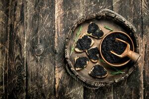 des sandwichs avec noir caviar sur le vieux plateau. photo