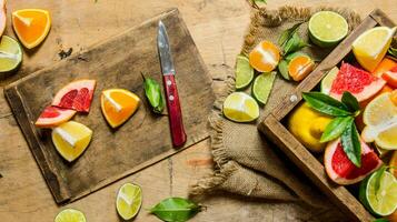 tranché agrumes des fruits - pamplemousse, orange, mandarine, citron, citron vert sur le vieux planche avec boîte. photo