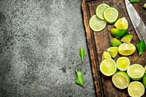 tranché Frais citrons verts sur une Coupe planche avec une couteau . photo