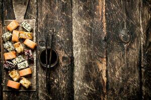 Japonais aliments. Rouleaux avec soja sauce. sur le vieux en bois Contexte. photo