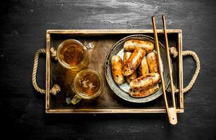 saucisses avec Bière sur une en bois plateau. photo