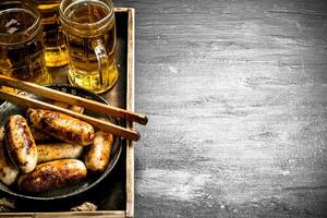 saucisses avec Bière sur une en bois plateau. photo