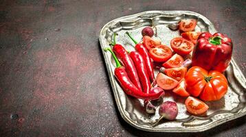 rouge biologique aliments. Frais chaud le Chili poivre, tomates et sucré poivre sur une acier plateau. photo