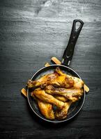 frit poulet jambes dans une friture poêle. photo