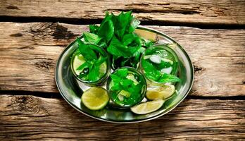 Frais cocktail de chaux, menthe, Rhum et la glace sur une métal plateau . sur une en bois tableau. photo