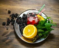 baie cocktail dans verre avec glace, citron et menthe feuilles sur une en bois table . photo