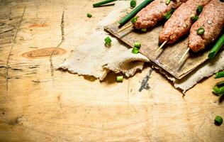 brut kebab avec vert oignons sur le planche. photo