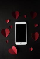 coeur et téléphone sur fond de mur noir. photo