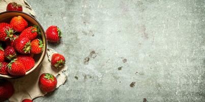 mûr des fraises dans bol sur vieux tissu. photo