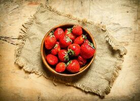 mûr des fraises dans bol sur une sac. photo