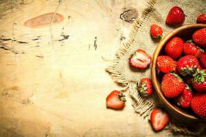 mûr des fraises dans bol sur une sac. photo