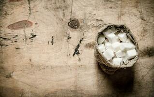 blanc raffiné sucre dans le sac. sur en bois Contexte. photo