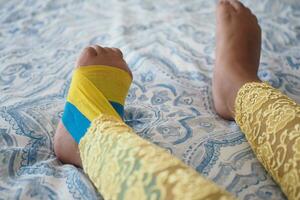 élastique thérapeutique Jaune et bleu ruban appliqué à enfant jambe. photo