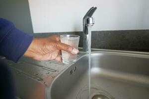 sale l'eau verser de une robinet robinet dans une verre, photo