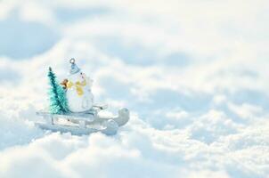 bonhomme de neige dans une traîneau avec une Noël arbre dans congères. hiver saison Contexte. photo