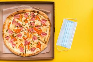 à emporter et livraison. prêt à manger Pizza dans papier carton boîte et protecteur masque sur Jaune Contexte photo