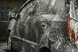 une gris voiture est étant laver dans une en libre service voiture laver gare. photo