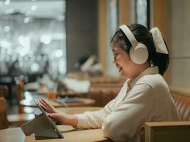 asiatique adolescent fille en utilisant tablette en train de regarder en ligne multimédia dans café magasin photo