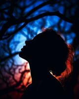 silhouette de une femme dans de face de une arbre à le coucher du soleil génératif ai photo