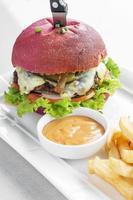 Snack-burger au fromage et à la betterave rouge avec frites et mayo chili sur plaque blanche