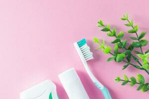 pastel rose Contexte avec nettoyage outils pour oral et dentaire santé se soucier tel comme brosse à dents, dentifrice, et soie. mode de vie et du quotidien routine pour une en bonne santé bouche et dents. photo