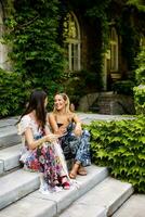 jolie Jeune femmes séance et en mangeant la glace crème par le vieux maison avec lierre photo