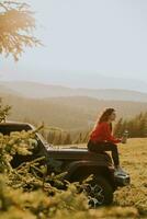 jeune femme se reposant sur un capot de véhicule tout-terrain à la campagne photo