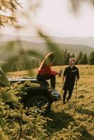 jeune couple se reposant près d'un capot de véhicule tout-terrain à la campagne photo