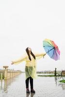 femme brune tenant un parapluie coloré attraper dans les gouttes de pluie photo