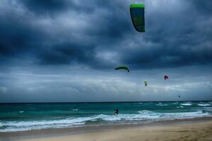 été paysage avec le océan avec foncé nuageux vagues et surfeurmi trousse avec parachutes flottant sur le rive photo