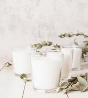 bougies blanches avec des feuilles d'eucalyptus sur fond de bois blanc
