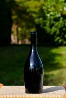 une noir bouteille séance sur une en bois table dans le Soleil photo