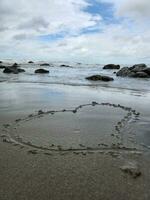 bord de mer sur une nuageux journée blanc sablonneux plage avec l'amour icône photo