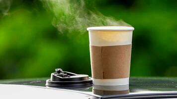 café à emporter dans une papier tasse sur Haut de le voiture toit vert arbre Contexte à lever du soleil dans le matin, sélectif se concentrer, doux se concentrer. photo