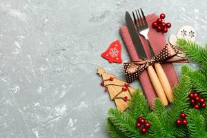 vue de dessus de fourchette et couteau sur serviette avec décorations de noël et arbre du nouvel an sur fond de ciment. concept de vacances et de fête avec espace de copie photo