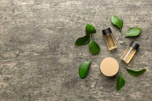 biologique cosmétique des produits avec vert feuilles sur ciment Contexte. copie espace, plat allonger photo
