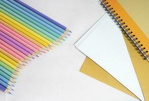 vague de coloré crayons, haut vue arc en ciel des crayons sur blanc et carnet arrière-plan, illustration, Contexte concept, éducation concept photo