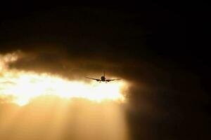 une avion en volant par le des nuages avec Soleil des rayons à venir par photo
