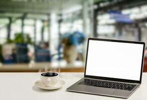une Vide blanc écran portable et café tasse sont mis sur une blanc bureau dans un bureau. le concept pour entreprise, technologie, l'Internet, conception, et art. fermer, sélectif se concentrer, flou Contexte photo